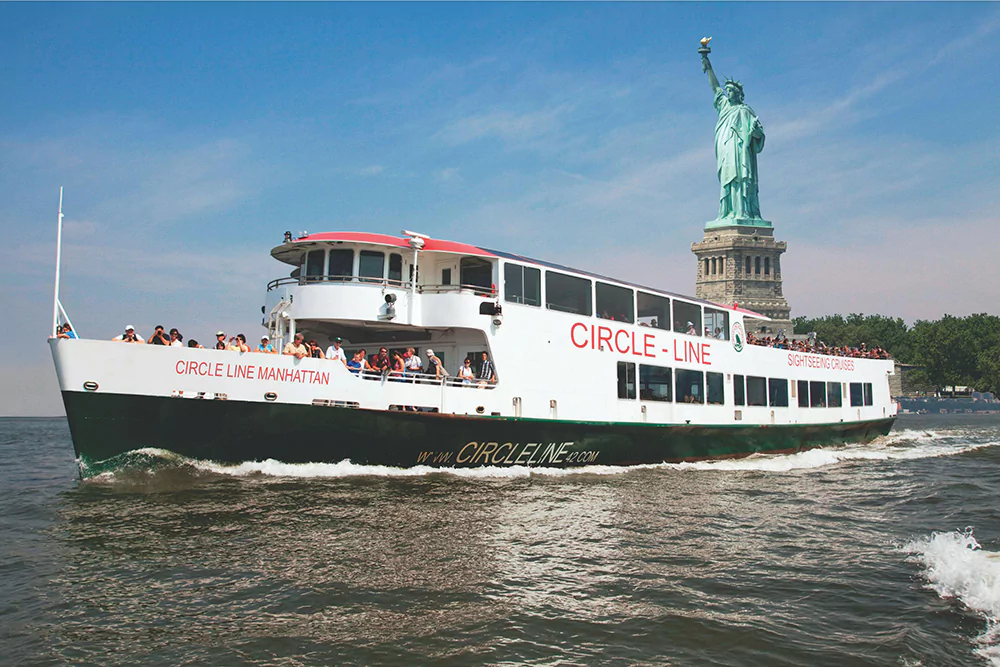 Large Tour Boat with Passengers floating in front of the Statue of Liberty