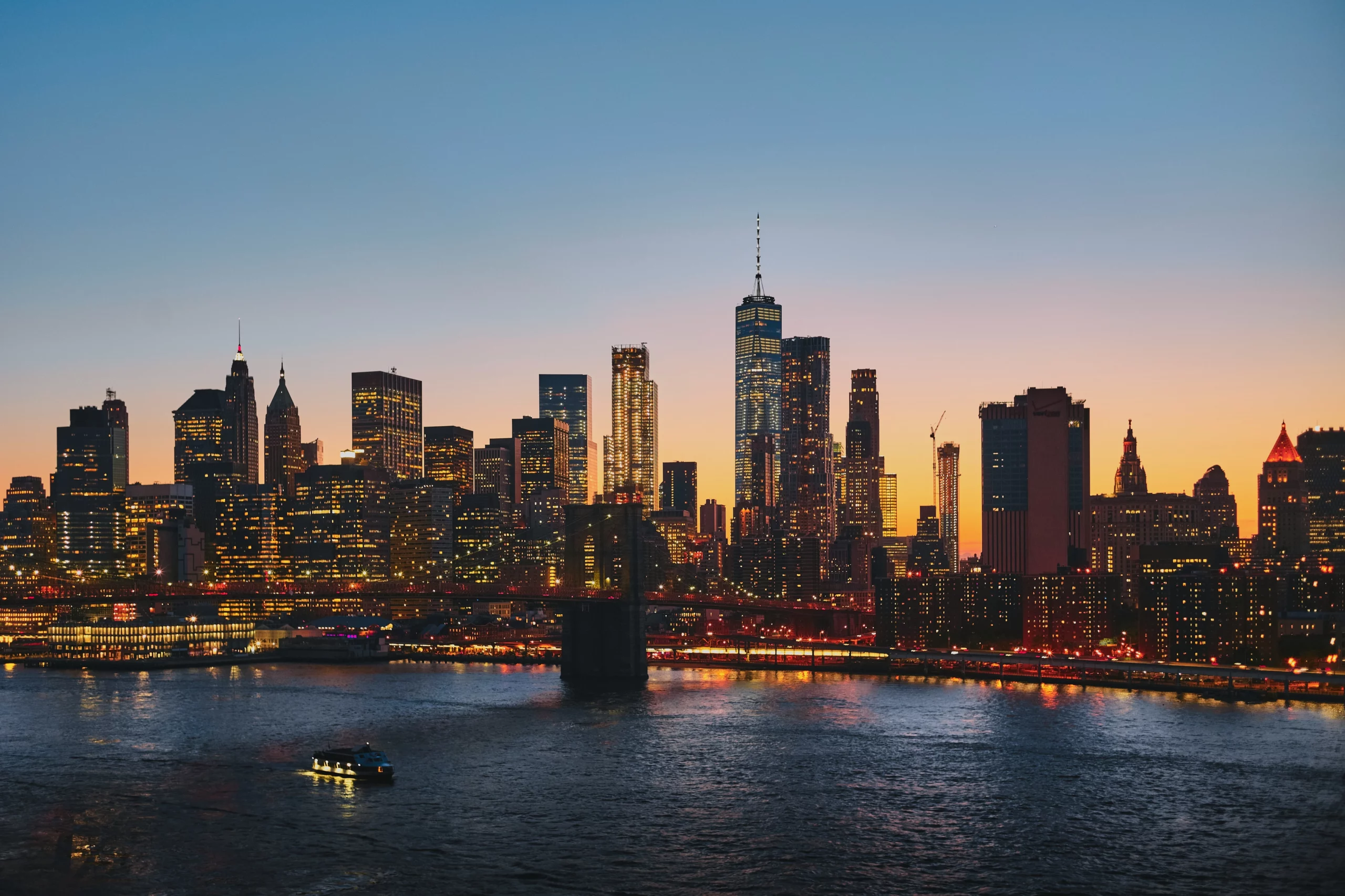 Skyline views at night of Manhattan and NYC highrises, luxury buildings, riverfront, and sunset dusk skies