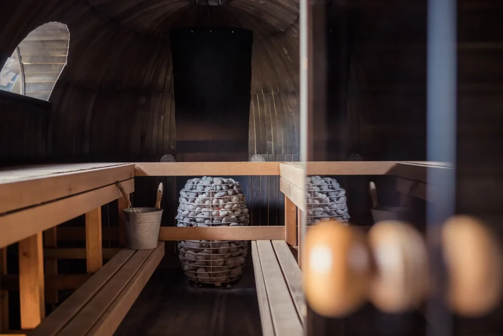 Sauna steam room with basket of hot rocks and small window to let in natural light 