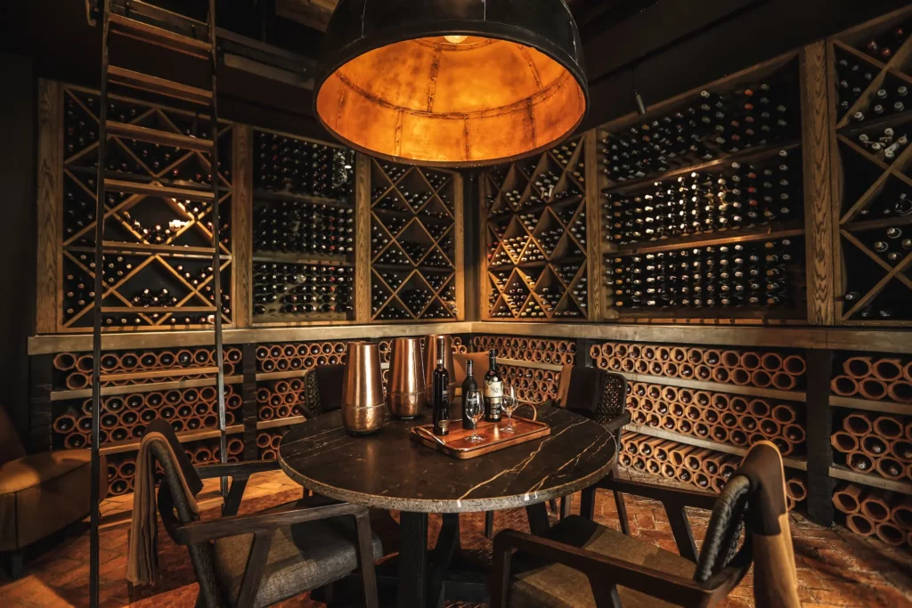 Luxury Wine Cellar & Tasting Room w/ Custom Wine Bottle Racks, Warm Wood Detailing, Cozy Tasting Table and Seating, and Brick Flooring